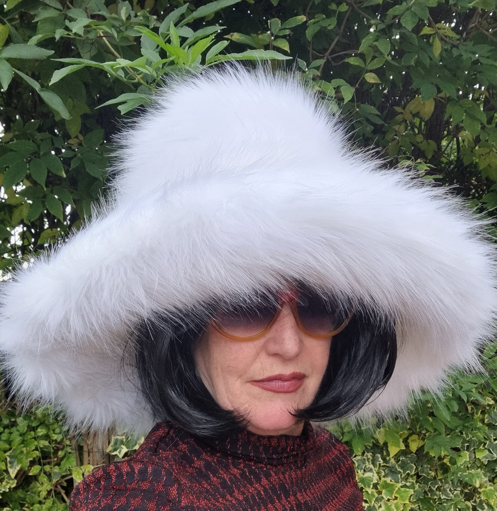 Person wearing a large white fur hat with a blurred background