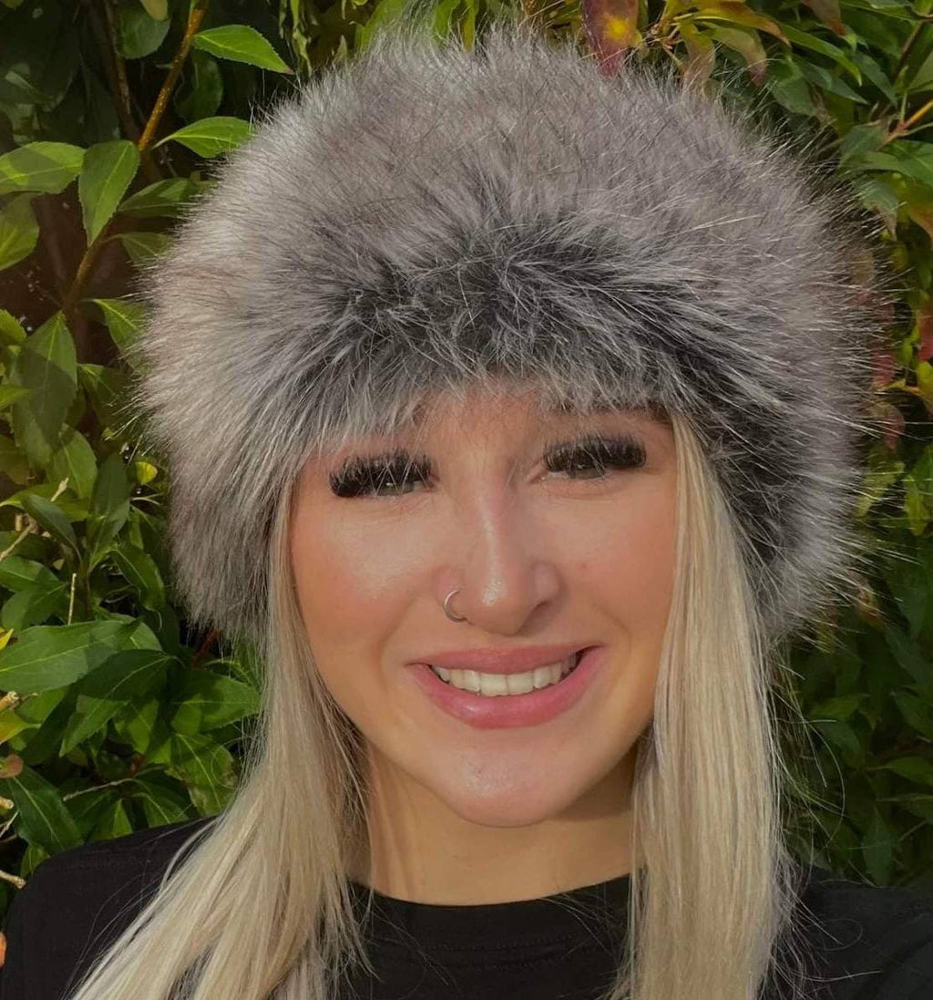 Person wearing a gray fur headband with a green leafy background