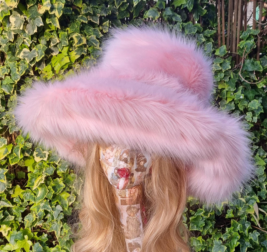 Person wearing a pink fur hat against a green ivy background