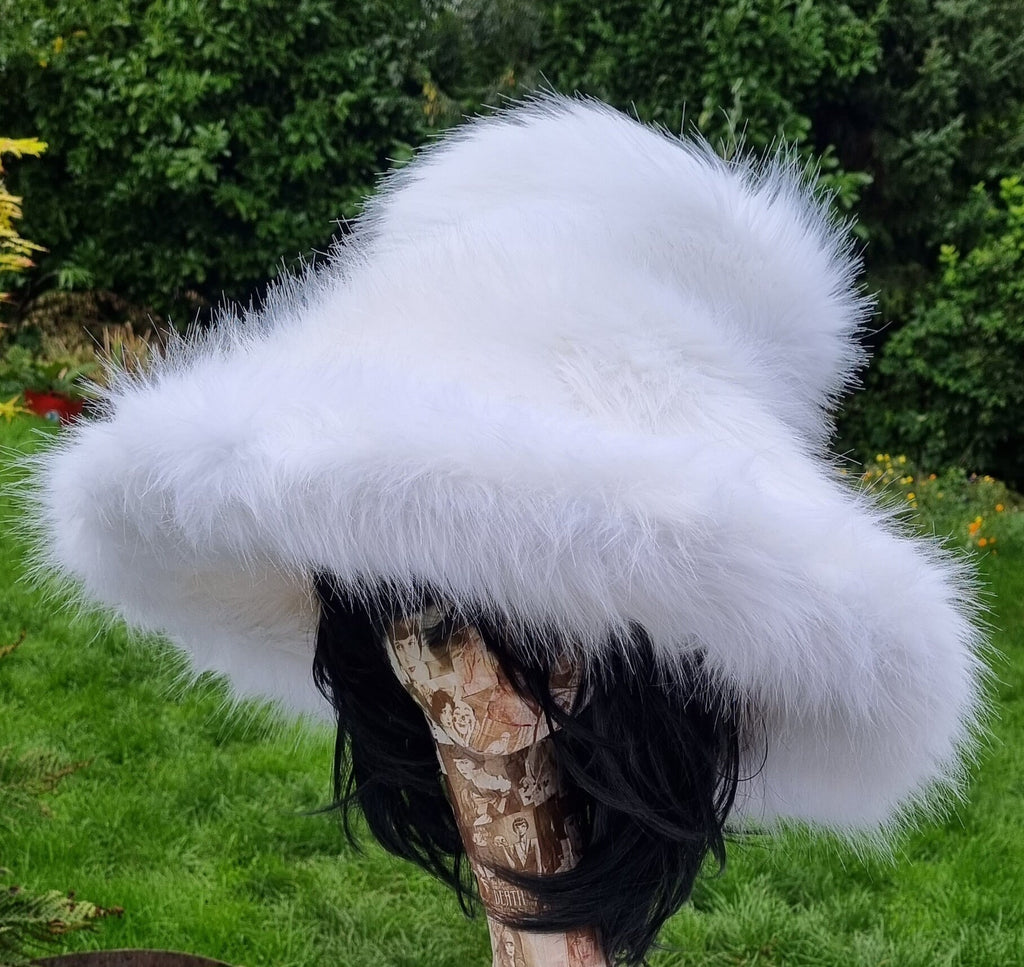 White fluffy hat on a mannequin against a green outdoor background
