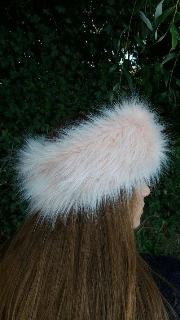Person wearing a fluffy pink hat against a green leafy background