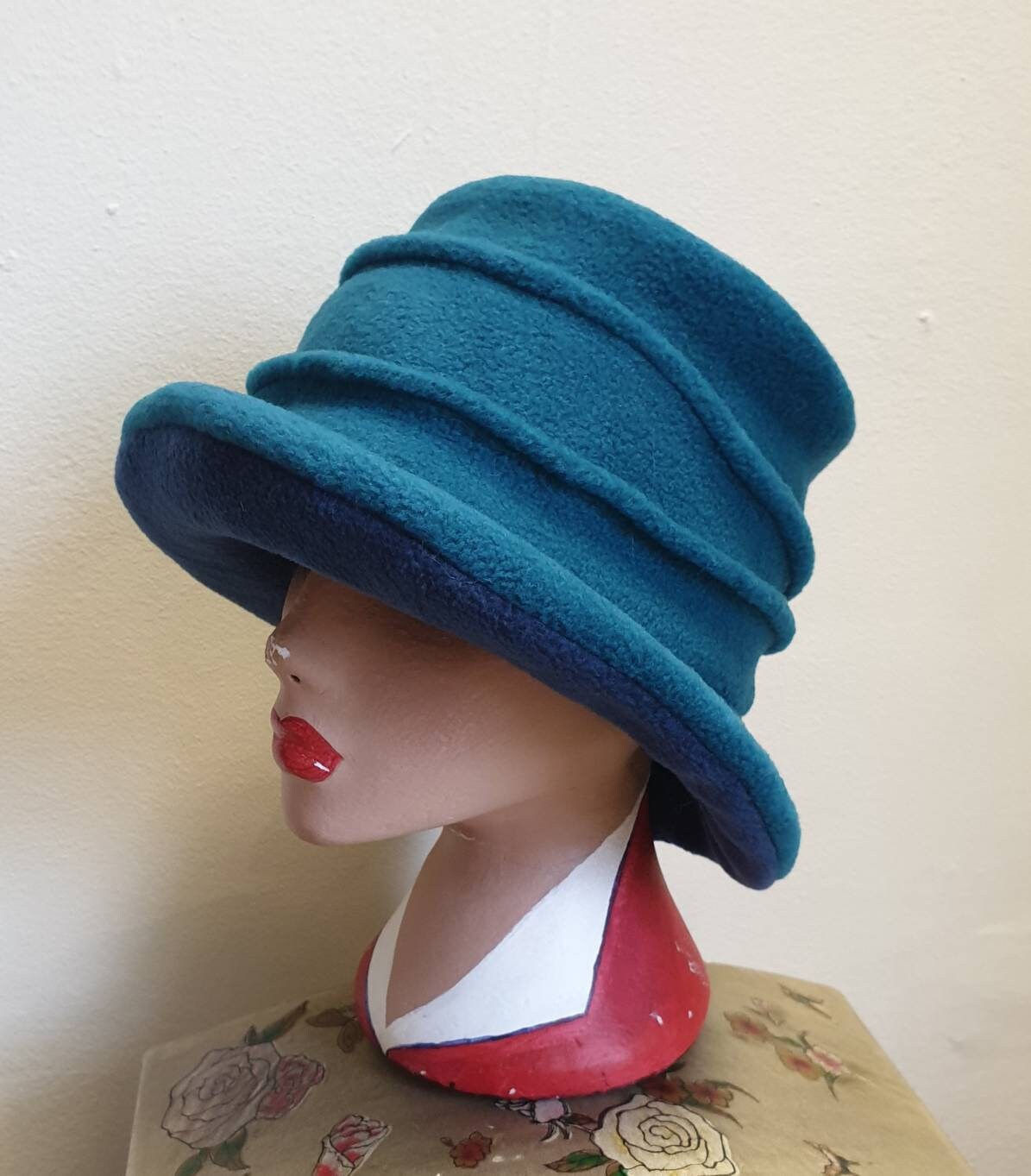 Teal green fleece cloche hat with no decoration, plain finish, worn on a mannequin head, handmade in England