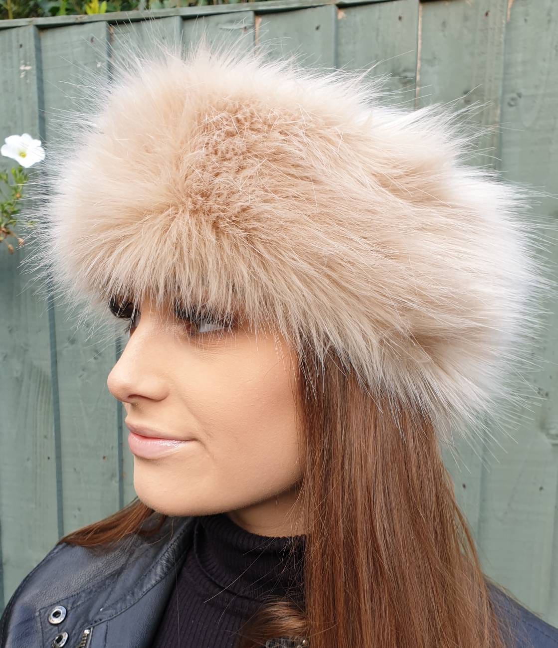 Woman wearing a fluffy beige headbandagainst a wooden fence background