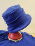 Blue hat on a mannequin head with a red and beige base against a beige background