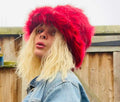 Deep red and black faux fur bucket hat — side view on model outdoors, rich deep red long-pile fur with subtle black-tipped strands, handmade in the UK