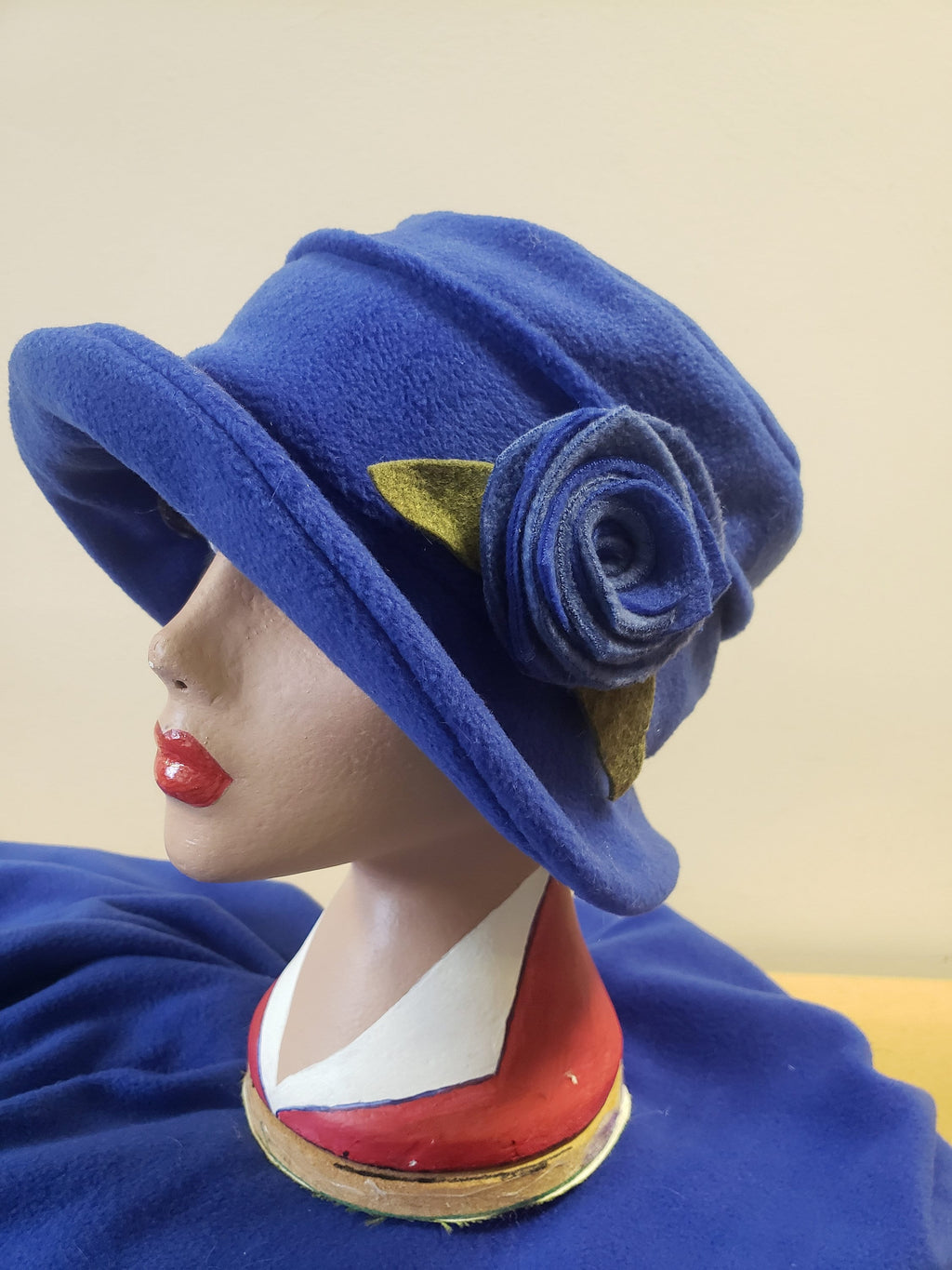 Blue hat with a flower on a mannequin head against a beige background