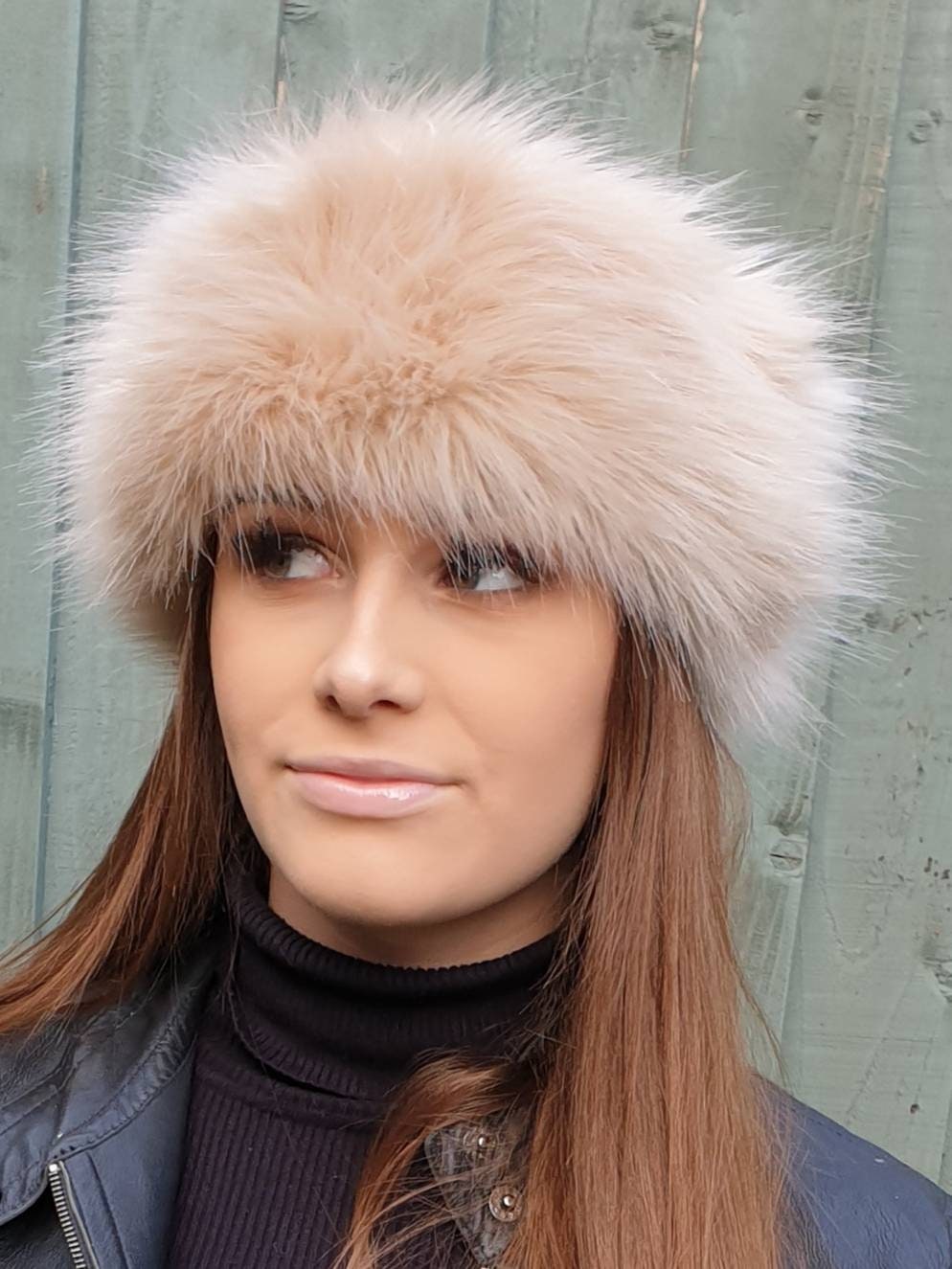 Woman wearing a fluffy beige fur headband against a light gray background