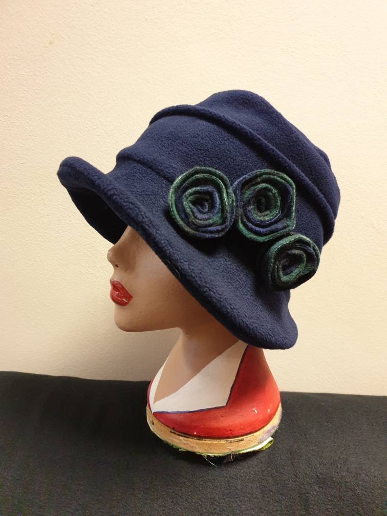 Navy blue hat with green floral details on a mannequin head against a beige background