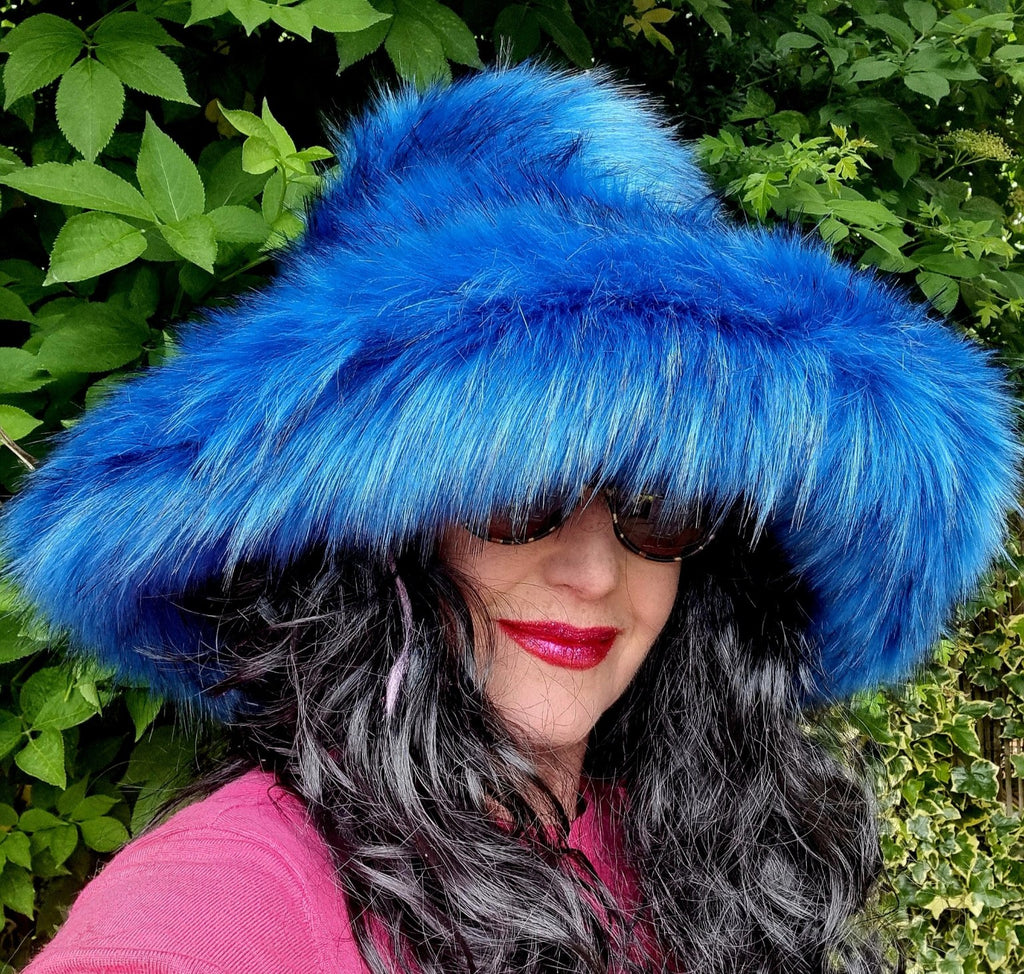 Person wearing a blue fur hat with a green leafy background