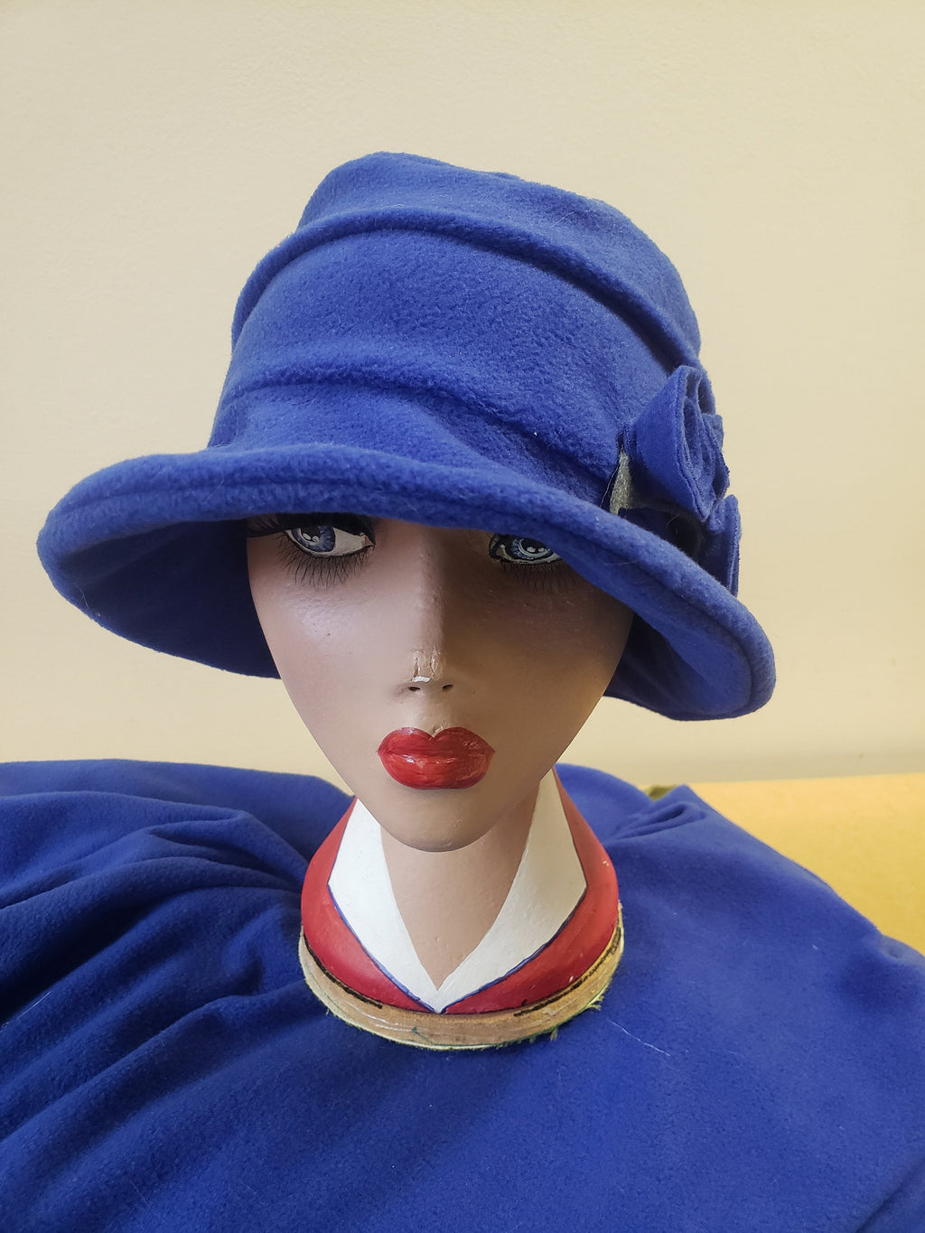 Mannequin head wearing a blue hat with a beige background