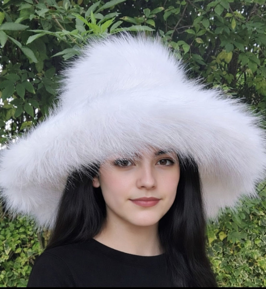 Person wearing a large white fur hat with a green leafy background