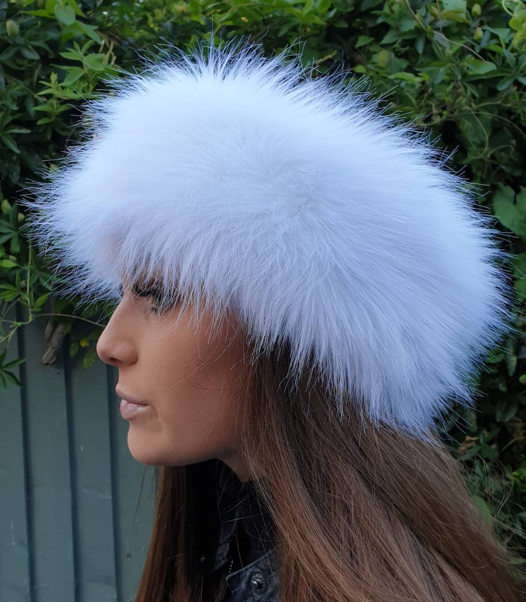 Person wearing a white fur headband against a green leafy background