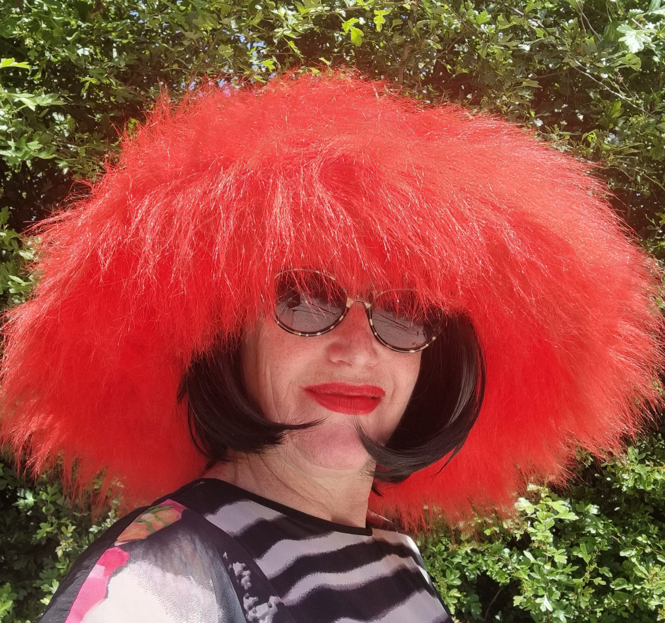 Person wearing a bright red hat and sunglasses with a blurred green background