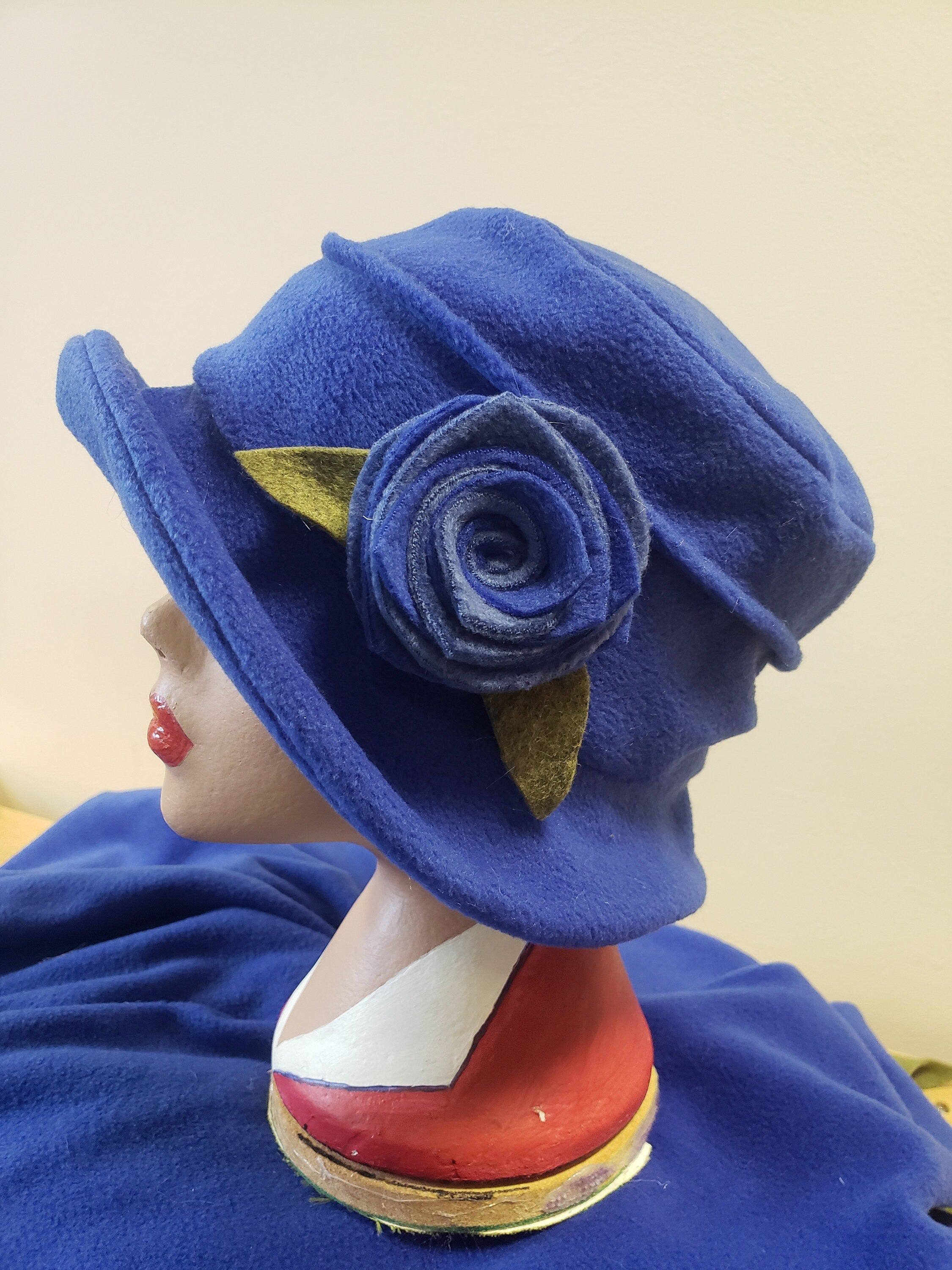 Blue hat with a flower on a mannequin head  with decorative flower detail
